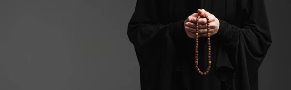 Cropped view of muslim nun with rosary praying isolated on dark grey, banner — Stock Photo