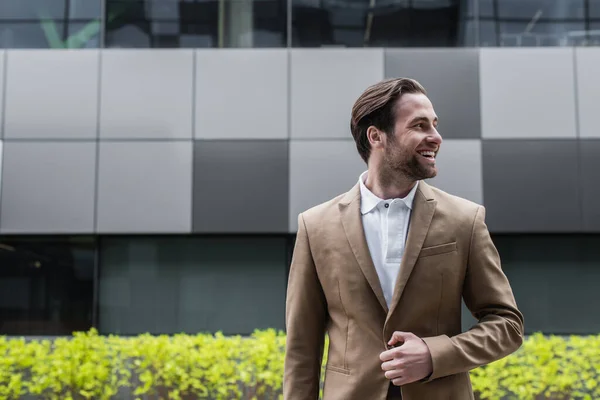 Cheerful businessman unbuttoning blazer and looking away outside — Stock Photo