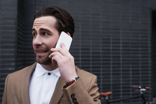 Young businessman in formal wear talking on smartphone outside — Stock Photo