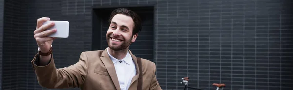 Felice giovane uomo d'affari in abito formale prendendo selfie sul cellulare fuori, banner — Foto stock