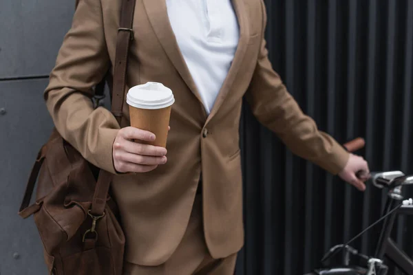 Vue recadrée d'un homme d'affaires tenant une tasse en papier près d'un vélo — Photo de stock