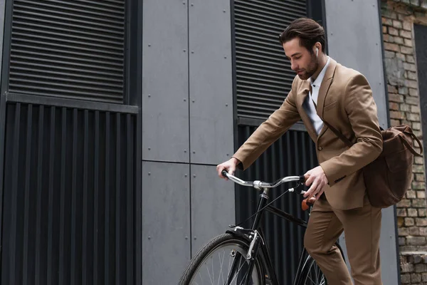 Homem de negócios barbudo em fones de ouvido andar de bicicleta fora — Fotografia de Stock