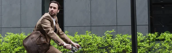 Homme d'affaires barbu dans des écouteurs à vélo à l'extérieur, bannière — Photo de stock