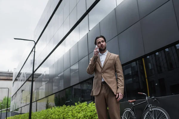 Low angle view of businessman talking on cellphone near building — Stock Photo