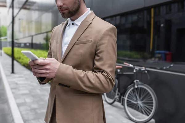 Vue recadrée d'un homme d'affaires barbu utilisant un smartphone à l'extérieur — Photo de stock