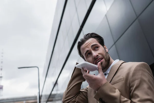 Bearded businessman recording voice message on smartphone outside — Stock Photo