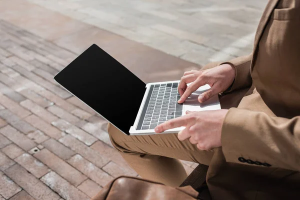 Vista recortada de hombre de negocios escribiendo en el ordenador portátil con pantalla en blanco - foto de stock