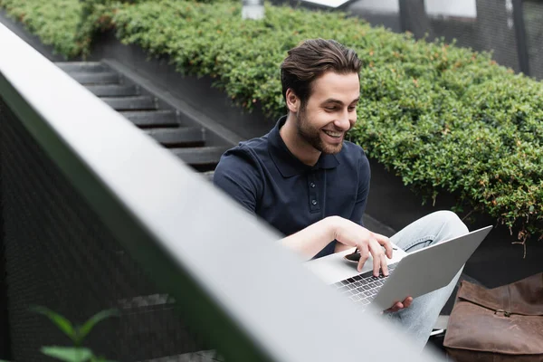 Glücklicher Mann lächelt, während er draußen Laptop benutzt — Stockfoto