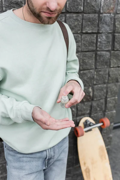 Vista recortada del hombre barbudo aplicando desinfectante en la mano - foto de stock