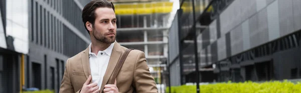 Uomo d'affari barbuto in giacca e cravatta con cinturino in pelle di borsa sulla strada urbana, banner — Foto stock