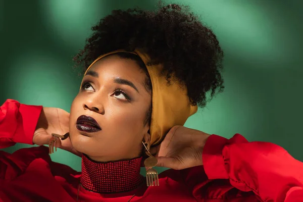 Portrait de jeune femme afro-américaine avec les mains près de la tête sur vert — Photo de stock