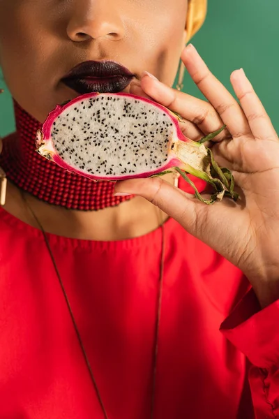 Vista parcial de la joven afroamericana sosteniendo medio corte de fruta de dragón en verde - foto de stock