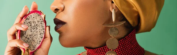 Abgeschnittene Ansicht einer jungen afrikanisch-amerikanischen Frau mit halbem Schnitt von Drachenfrüchten auf grün, Banner — Stockfoto