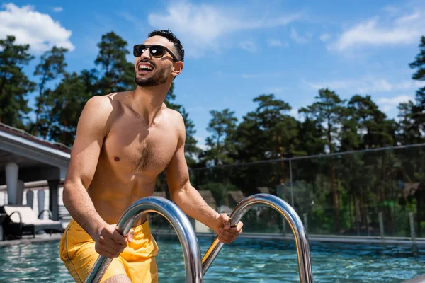 Hombre árabe alegre de pie cerca de la piscina en el complejo - foto de stock