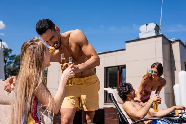Feliz interracial amigos no swimwear clinking com cerveja ao ar livre — Fotografia de Stock