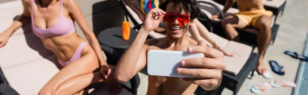 Blurred man taking selfie near friends in swimwear, banner — Stock Photo