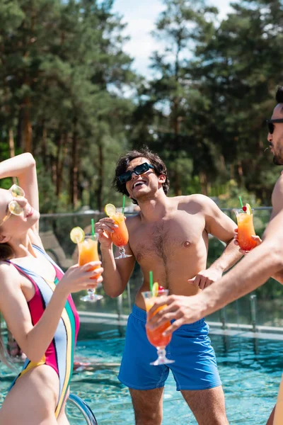 Glücklicher Mann mit Cocktail steht am Wochenende neben multiethnischen Freunden und Schwimmbad — Stockfoto