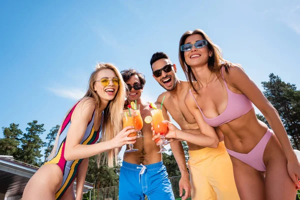 Low angle view of happy interracial friends with cocktails at resort — Stock Photo