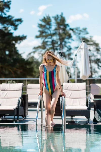 Mulher de fato de banho caminhando para piscina ao ar livre — Fotografia de Stock