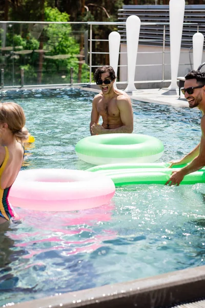 Amigos multiculturales alegres pasar tiempo en la piscina en el complejo - foto de stock