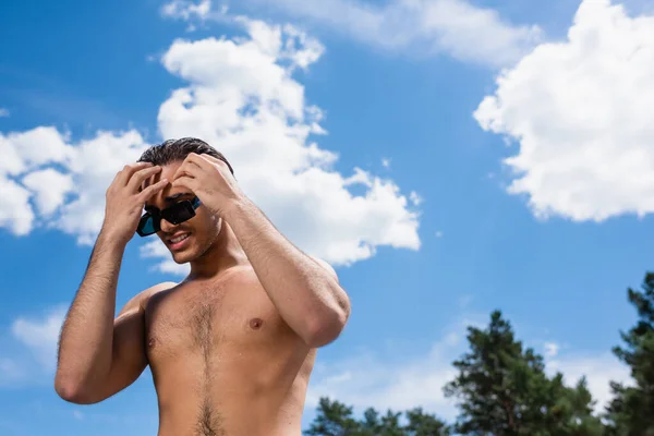 Baixo ângulo de visão do homem sem camisa tocando o cabelo ao ar livre — Fotografia de Stock