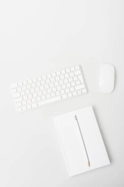 Top view of computer mouse, keyboard and notebook with pencil isolated on white — Stock Photo