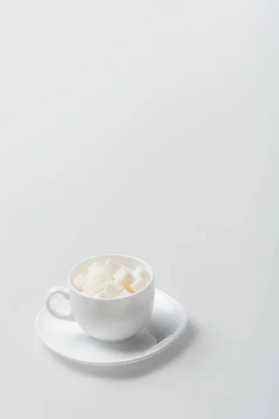 Terrones de azúcar en taza con platillo sobre blanco - foto de stock