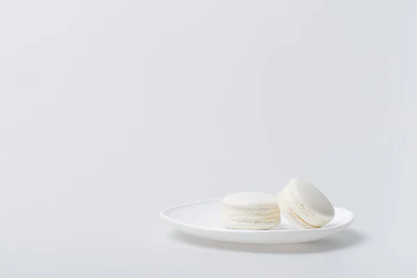 Deliciosos macarons en plato aislado en blanco - foto de stock