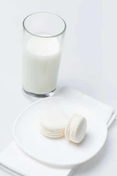Delicious macarons on plate near glass of milk isolated on white — Stock Photo