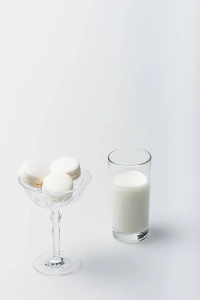 Tasty macarons in dessert dish near glass of milk on white — Stock Photo