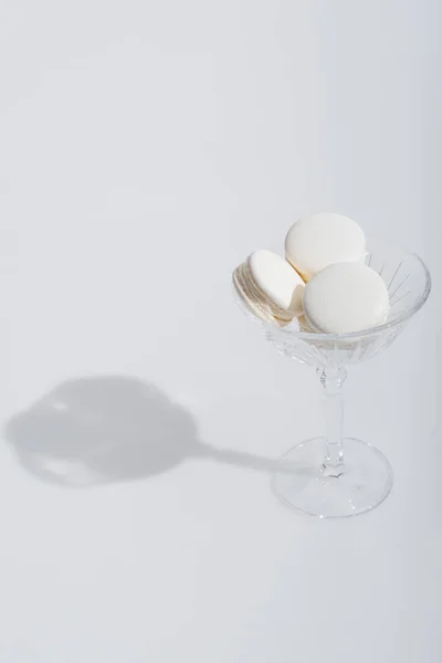 Sombra perto de macarons saborosos no prato de sobremesa no branco — Fotografia de Stock