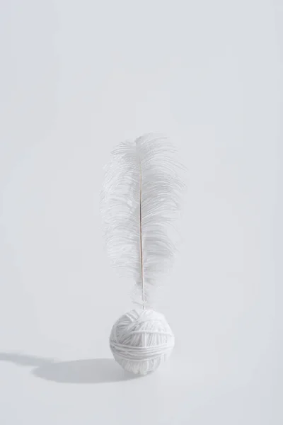 Lightweight and soft feather near ball of thread isolated on white — Stock Photo