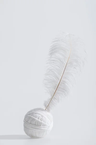 Weightless and soft feather near ball of thread isolated on white — Stock Photo