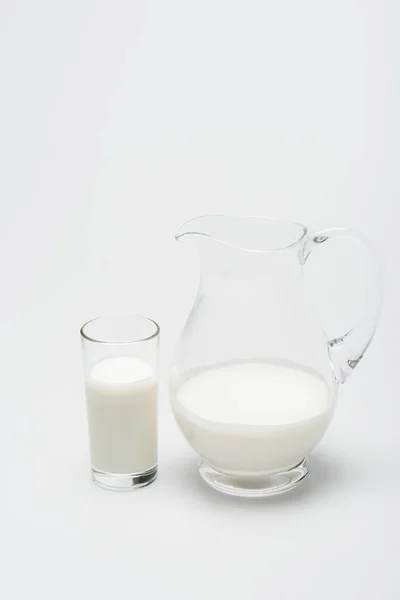 Glas Milch und Krug auf weißem Hintergrund — Stockfoto