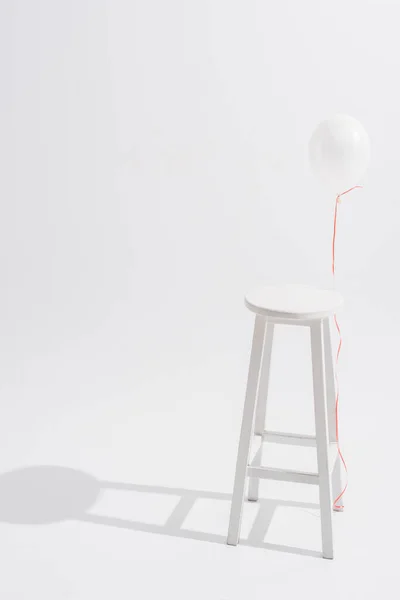 Balloon near high wooden stool on white background — Stock Photo