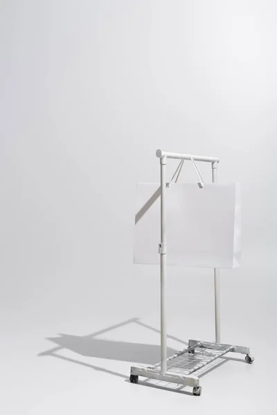 Shopping bag hanging on garment rack on grey — Stock Photo