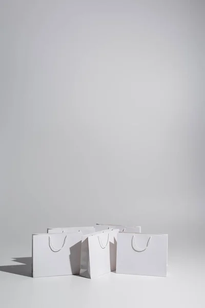 White shopping bags with purchases on grey background — Stock Photo