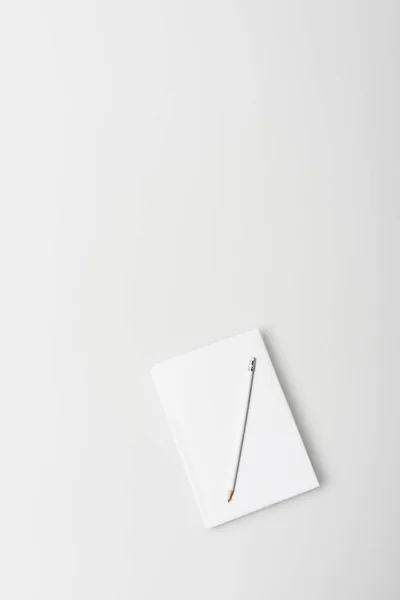 Вид зверху ноутбука в твердій обкладинці з олівцем ізольовано на білому — стокове фото