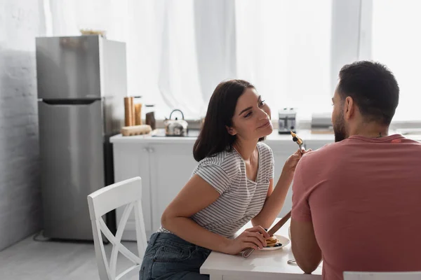 Positive young couple eating pancakes together in kitchen — Stock Photo