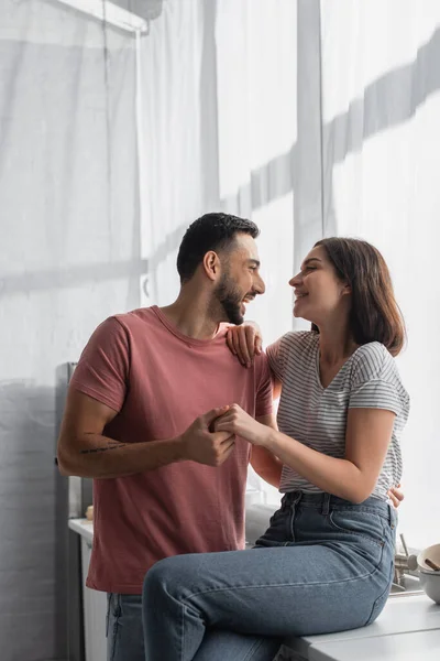 Smiling young couple looking at each other and holding hands in kitchen — Stock Photo