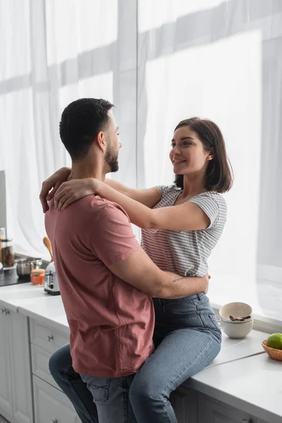 Smiling young couple looking at each other and hugging in kitchen — Stock Photo