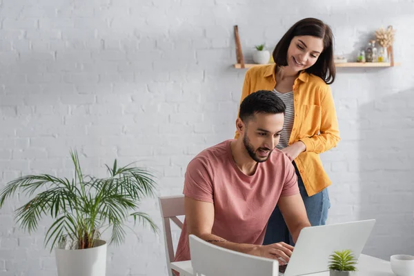 Lächelndes junges Paar in lässiger Kleidung schaut zu Hause auf Laptop — Stockfoto