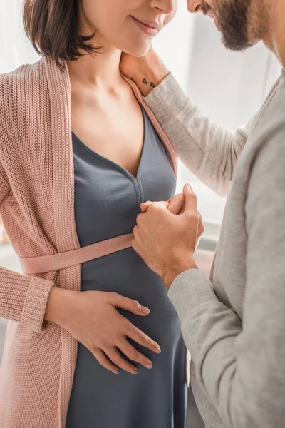 Teilbild eines jungen Mannes, der Schwangere zu Hause sanft an der Hand hält — Stockfoto