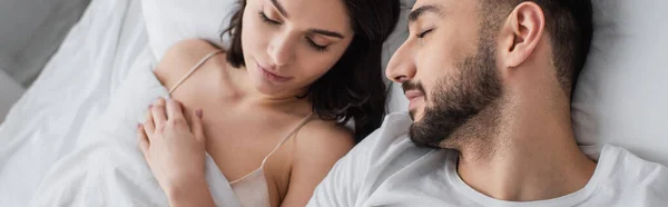 Vista ad alto angolo di giovane coppia che dorme su biancheria bianca in camera da letto, banner — Foto stock