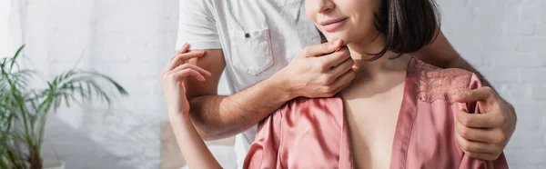 Vista parcial de pareja joven abrazándose suavemente en el dormitorio, pancarta - foto de stock