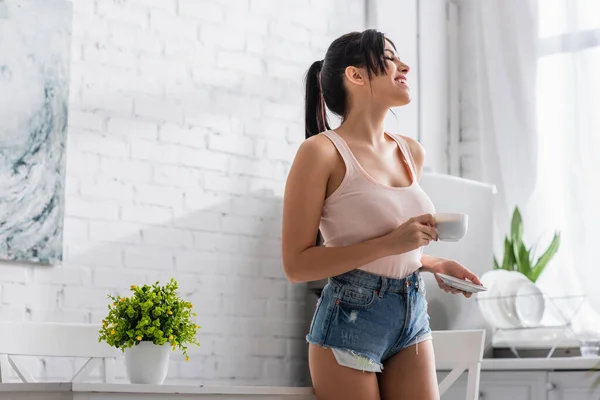 Jovem feliz segurando xícara de café e pires — Fotografia de Stock