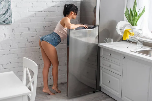 Брюнетка и сексуальная женщина наклоняются над холодильником — стоковое фото