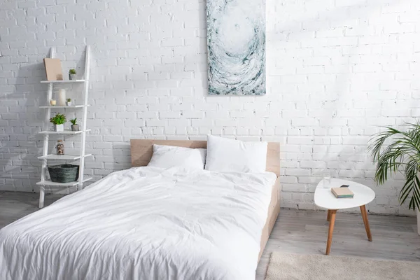 Cama con ropa de cama blanca en el dormitorio moderno - foto de stock