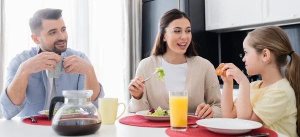 Щаслива сім'я розмовляє під час сніданку на кухні, банер — стокове фото