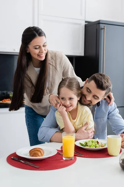 Mann umarmt Tochter beim Frühstück in der Nähe von glücklicher Frau — Stockfoto